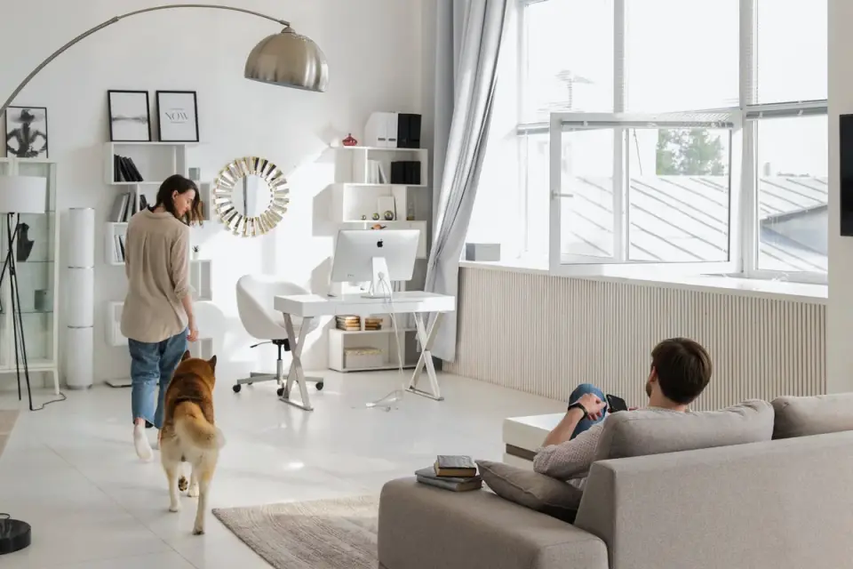 A couple seated at a table looking at a laptop screen while their small dog sits beside them