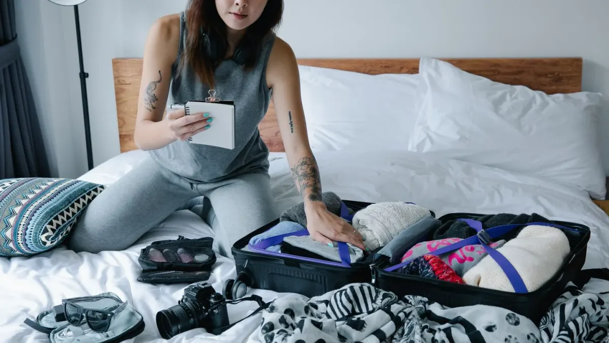 A dog lying near an open suitcase while an owner packs