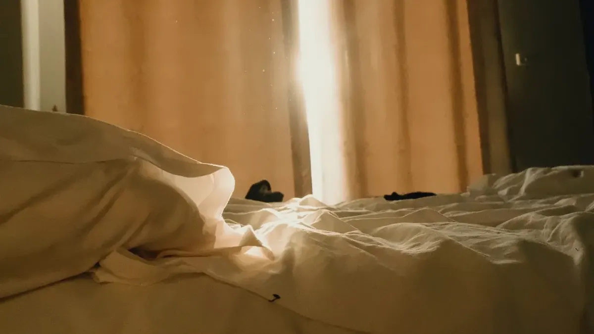 A golden retriever lying calmly on a hotel bed beside an open suitcase