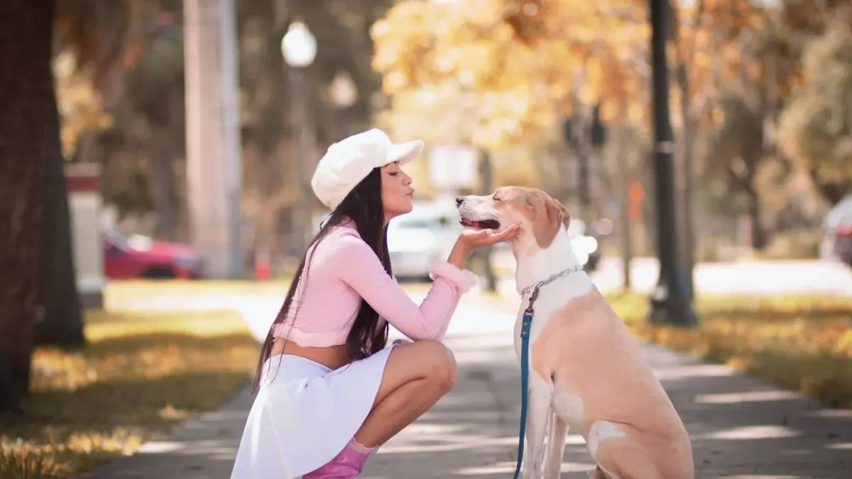 A pet sitter kneeling to greet a dog at the front door while the owner reviews a checklist