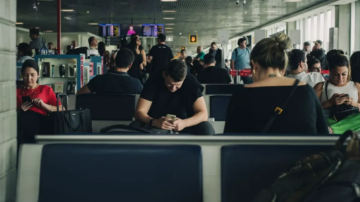 A traveler reviewing paperwork beside a dog carrier at an airport departure gate