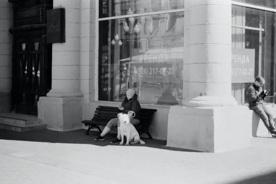 A woman on a phone call standing next to a packed suitcase and her dog